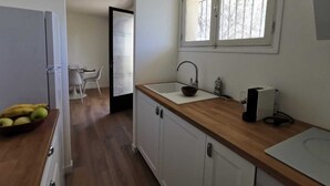 A kitchen with a wooden countertop, a sink, and a window with a metal grill. - Bas de Villa au Calme (Villeneuve-Loubet)