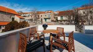 A rooftop terrace with a table and chairs, a barbecue grill, and a view of surrounding buildings. - Boutique Apartments Imotski 2 (Imotski)