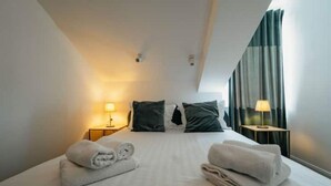 A hotel room with a neatly made bed, two bedside lamps, and a view of the outside through curtains. - Boutique Apartments Imotski 2 (Imotski)