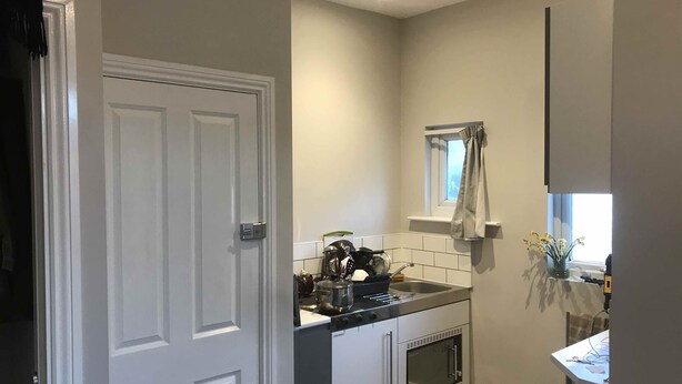 A compact kitchen with a built-in oven, a window with a curtain, and a small sink. - Studio with a view, great transport links to central London (London)
