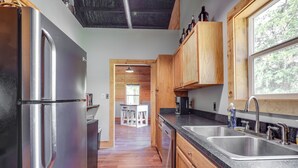 A modern kitchen with stainless steel appliances, wooden cabinets, and a granite countertop. - Fish & Relax! Magnolia River Cabin Hideaway (Magnolia Springs)