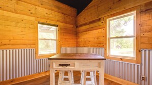 A wooden cabin interior with a central table, two windows, and a radiator. - Fish & Relax! Magnolia River Cabin Hideaway (Magnolia Springs)