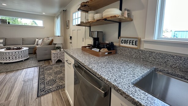 Une cuisine moderne dotée de plans de travail en granit, d’un coin café et d’un espace repas comprenant un canapé et une table basse.