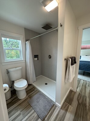 Une salle de bain moderne équipée d’une douche, de toilettes et d’une fenêtre.