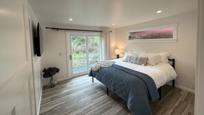 Une chambre à coucher avec un lit, une fenêtre, une porte et un téléviseur fixé au mur.