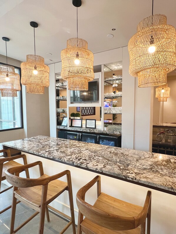 A modern kitchen with a granite countertop, wooden bar stools, and three woven pendant lights. - Memphis Vitality Hotel (Memphis)
