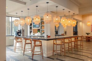 Een moderne keuken met een centraal eiland, barkrukken en hanglampen.