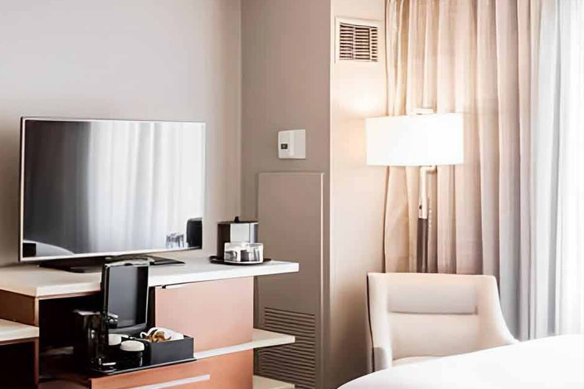 Een hotelkamer met een bed, een bureau met een televisie, een stoel en een lamp.