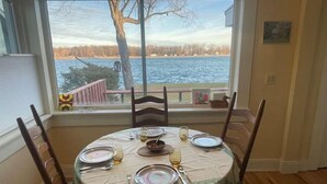 Mesa de comedor para cuatro con vista a un lago a través de una ventana.