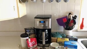 Una cocina con cafetera, filtros de café, tetera y una taza de té.