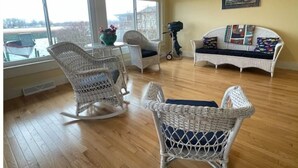 Una habitación con muebles de mimbre, vista al exterior y un cuadro en la pared.