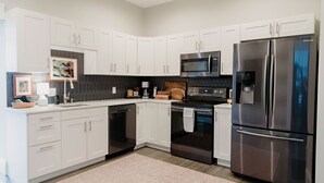Una cocina moderna con armarios blancos, un refrigerador de acero inoxidable, un microondas y un horno.