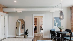 Una sala de estar moderna con comedor, un espejo grande y una lámpara colgante.