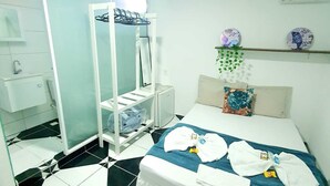 Una habitación de hotel con cama, baño y un estante con artículos de aseo.