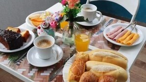 Una mesa de desayuno con platos de comida, una taza de café y un jarrón con flores.