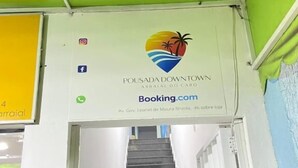 Una escalera conduce a una habitación con un cartel de Pousada Downtown, que muestra una opción de reserva.