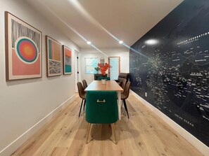 Enjoy meals in this stylish dining area with a long table, comfortable chairs, and beautiful artwork on the walls.