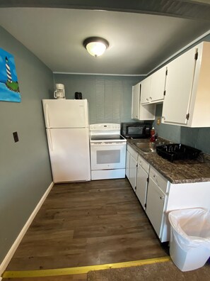 A compact kitchen with white appliances, a microwave, and a coffee maker on the countertop. - 2 bedrooms with shared pool. apt3 (Hampton)