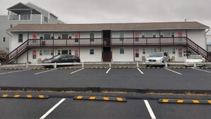 Ein Motel mit Parkplatz, ein zweistöckiges Gebäude und eine Treppe, die zu der oberen Etage führt.
