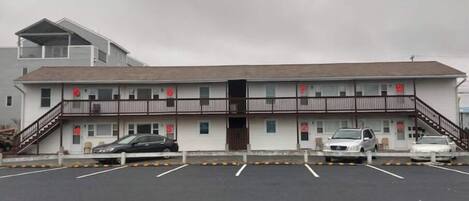 A motel with a parking lot, a two-story building, and a staircase leading to the upper floor.