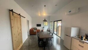 A modern kitchen with a dining area, a wooden door, and a refrigerator.