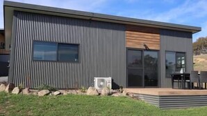 A modern, single-story building with a flat roof, large windows, and a small patio area.