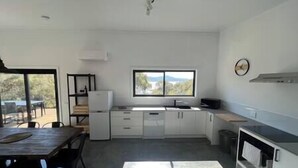 A modern kitchen with white cabinets, a built-in oven, and a window overlooking a scenic landscape.