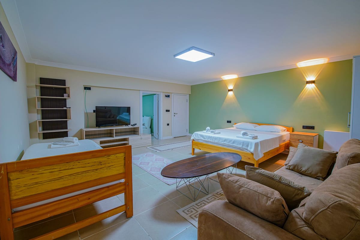A modern hotel room with a bed, sofa, TV, and a desk.