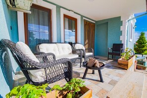 A balcony with wicker furniture, a small table, and potted plants. - Keyf-i Ada Bozcaada (Bozcaada)