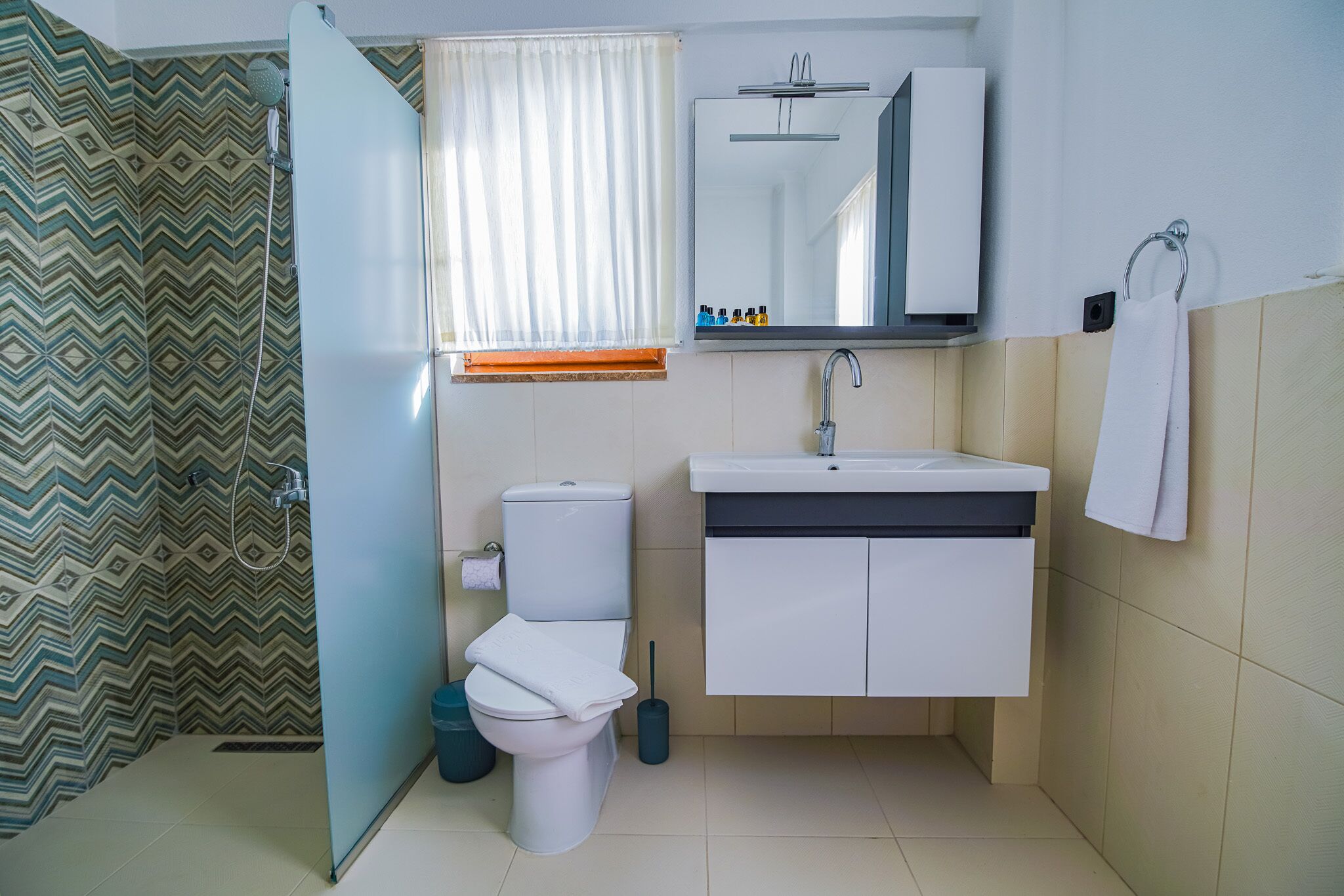 A bathroom with a toilet, sink, and mirror.