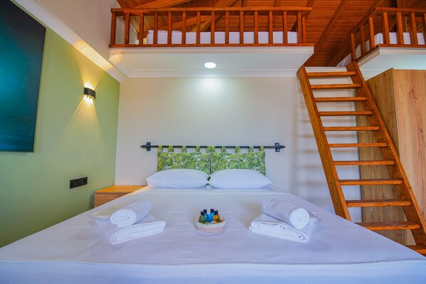 A hotel room with a bed, a wooden ladder, a headboard with a leaf pattern, and a wall-mounted light. - Keyf-i Ada Bozcaada (Bozcaada)
