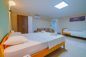 A bedroom with two beds, a wardrobe, a bedside table, and a painting on the wall. - Keyf-i Ada Bozcaada (Bozcaada)