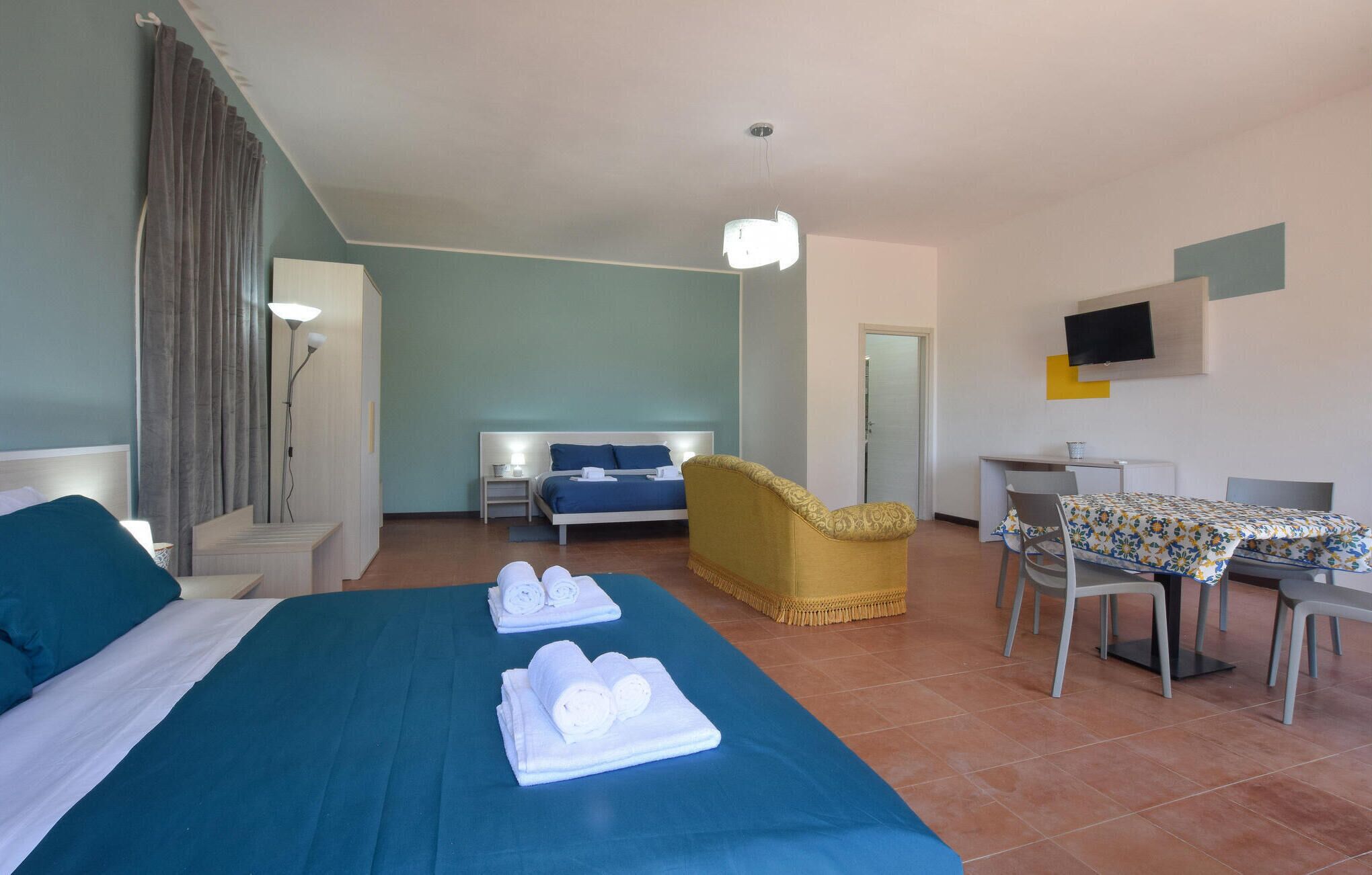 Habitación de hotel con cama, escritorio, silla, televisión y baño.