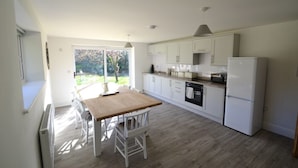 Una cocina moderna con armarios blancos, una mesa de comedor de madera y un horno empotrado.