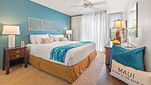 A hotel room with a bed, two nightstands, a ceiling fan, and a view of the outdoors. - Hale Kamaole #166, VIEW, No Steps to Entry, Pool, A+ Wi-Fi, King Bed, EZ Parking (Kihei)