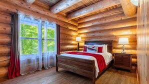 A wooden cabin bedroom with a bed, two bedside tables, and a window with curtains. - Fiddler Lake Resort - Moose 93 (Mille-Isles)