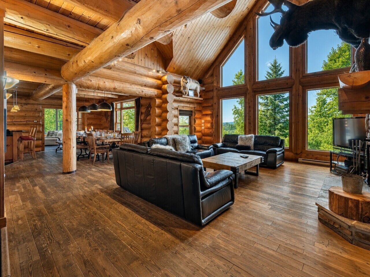 Un intérieur spacieux de chalet en bois, comprenant un grand salon, un coin repas et une cheminée.