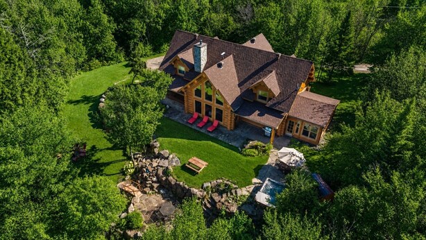 A large log cabin with a spacious deck and hot tub, surrounded by lush greenery. - Fiddler Lake Resort - Moose 93 (Mille-Isles)