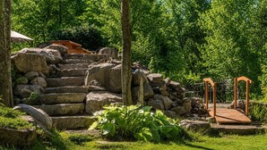 A stone staircase leading to a wooden bridge over a small stream, surrounded by lush greenery. - Fiddler Lake Resort - Moose 93 (Mille-Isles)