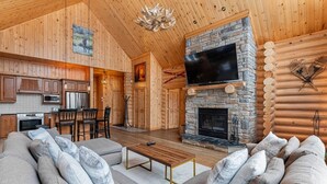 A log cabin interior with a stone fireplace, wooden furniture, and a television. - Fiddler Lake Resort - Elk 96 (Mille-Isles)