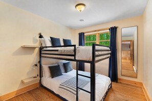 A bunk bed room with a window, a mirror, and a ceiling light.