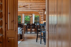 Un interno in legno con zona pranzo, divano e ampie finestre.