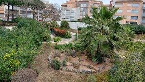 A residential area with multi-story buildings, a landscaped garden with various plants and a palm tree, and a clear sky. - Meublé de Tourisme 3 Étoiles en Résidence Sécurisé (Cap d'Agde)