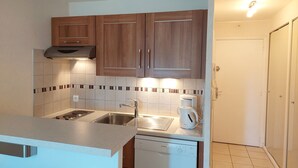 A compact kitchen with wooden cabinets, a Bosch dishwasher, and a coffee maker. - Meublé de Tourisme 3 Étoiles en Résidence Sécurisé (Cap d'Agde)