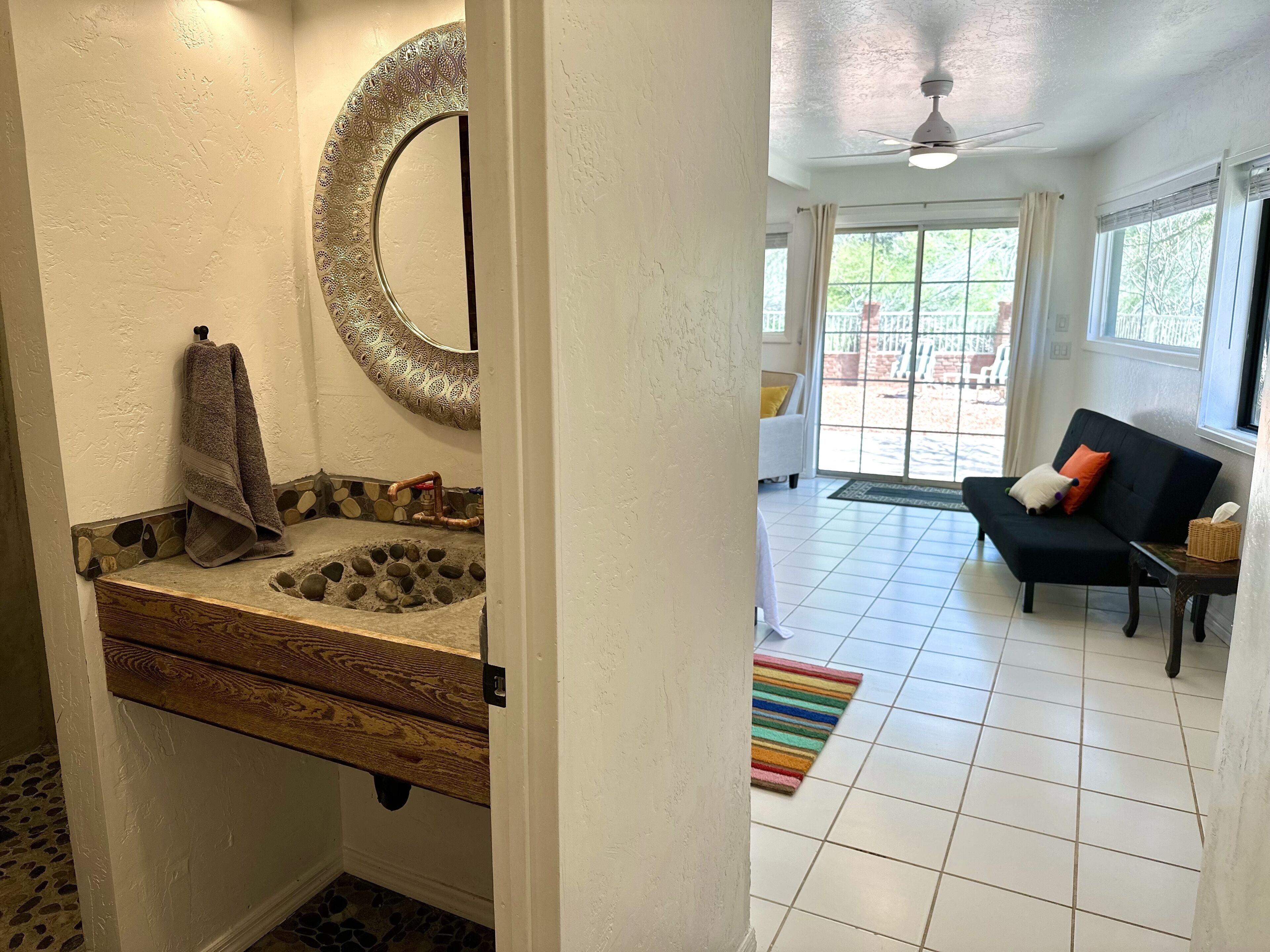 A bathroom with a wooden vanity, a large mirror, and a towel hanging on the wall.