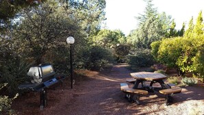 A gravel path leading to a picnic table with a grill, surrounded by dense foliage and trees. - Capital Vacations Sedona Springs Resort - 2 Bedroom (7-Night) (Sedona)
