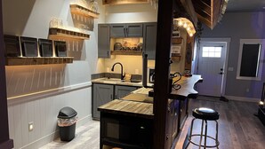 A modern kitchen with wooden shelves, a built-in oven, and a bar area with stools. - Your Very Own Sports Bar! (Post Falls)