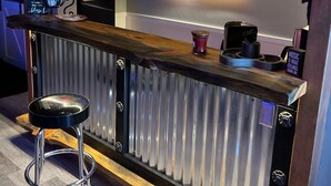 A bar area with a wooden counter, bar stools, and a refrigerator. - Your Very Own Sports Bar! (Post Falls)