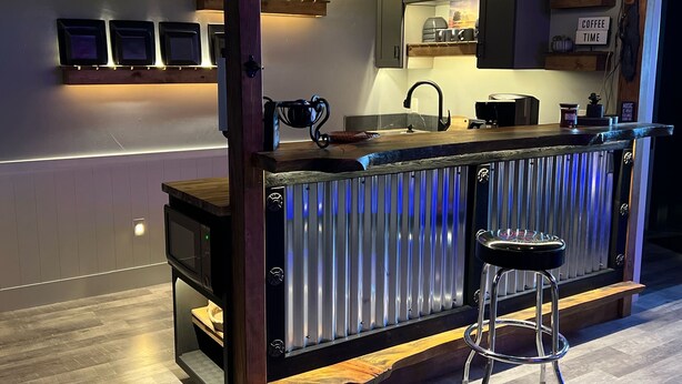 A modern kitchen with a bar area, stainless steel appliances, and a wooden bar counter. - Your Very Own Sports Bar! (Post Falls)