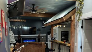 A modern living room with a fireplace, a motorcycle, a bar area, and a staircase leading to another level. - Your Very Own Sports Bar! (Post Falls)
